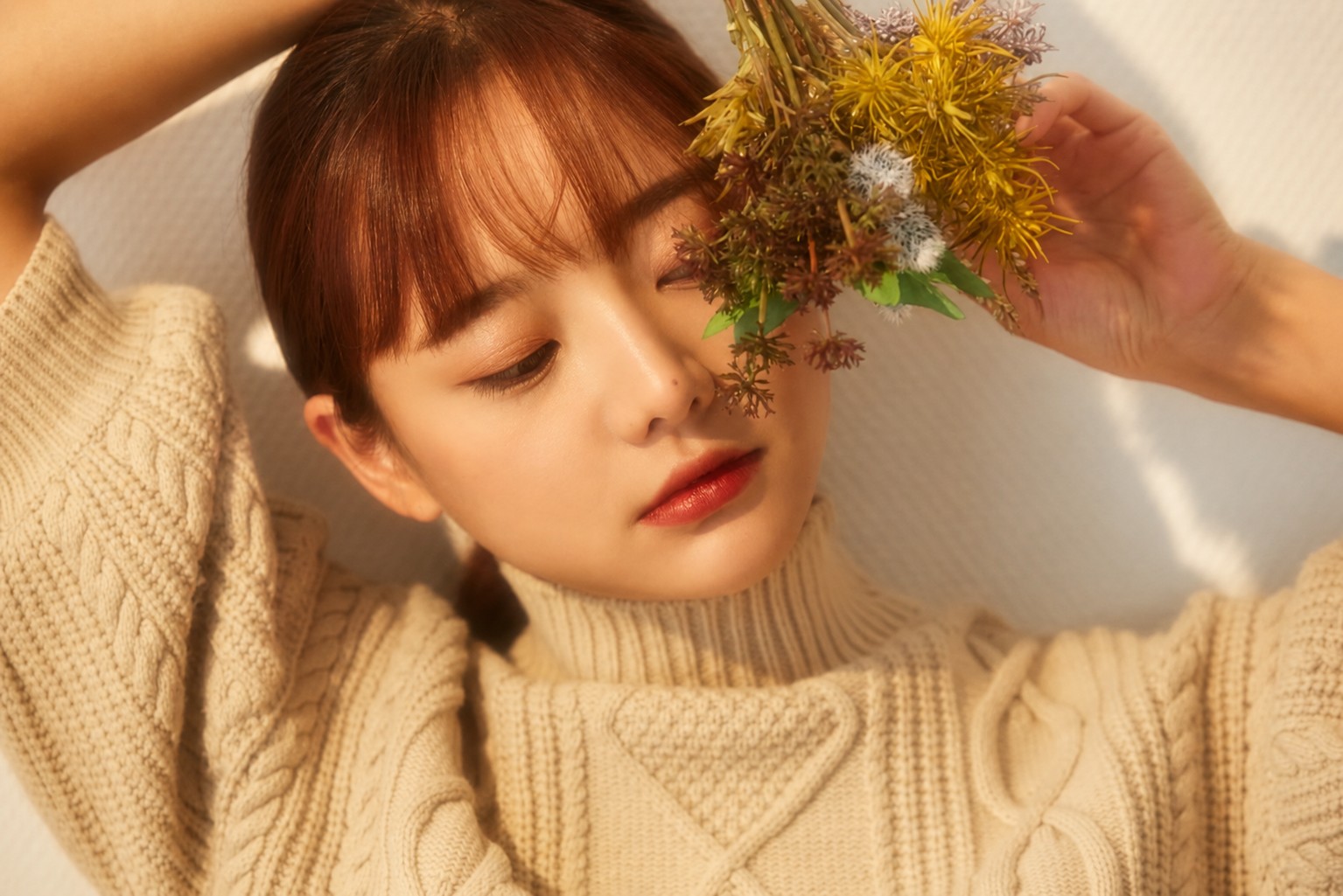 따뜻한 햇살 아래 꽃을 들고 눈을 감은 여성의 자연스러운 포트레이트